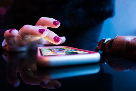 Fingers poised over a smartphone screen ready to select an app